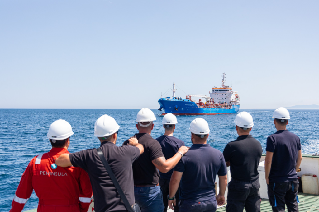 Peninsula crew members on deck watching a bunker tanker during operations.